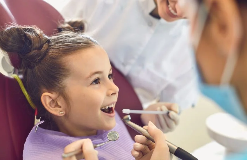 Niña sonriente en una consulta dental infantil durante una revisión con especialistas en odontología, en el contexto de un tratamiento de fenestración dental en niños.