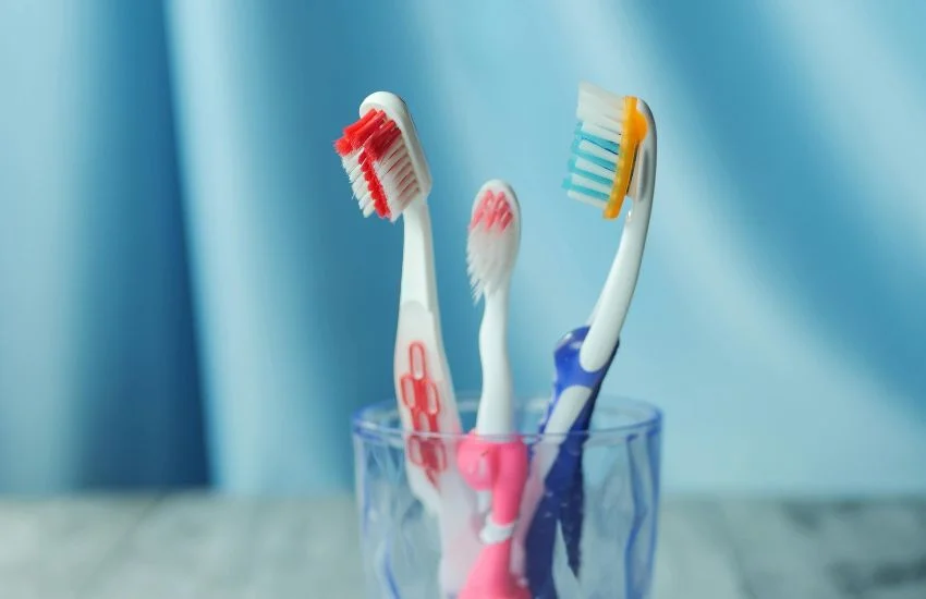 Cepillos de dientes en un vaso, representando errores comunes en la higiene dental diaria como el uso prolongado o el mal almacenamiento.