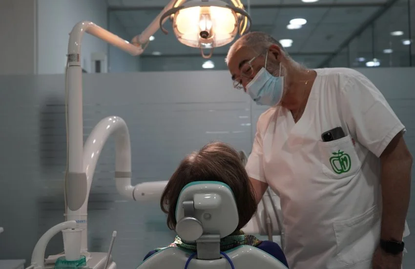 Dentista en la clínica dental de Zaragoza Doctor Toledo haciéndole una valoración a una paciente para descartar una elección de materiales en consulta para planificar un tratamiento tras sospecha de alergias a materiales dentales.