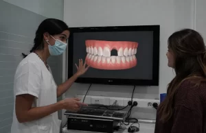 Profesional explica con un modelo dental las opciones para reponer un diente ausente.
